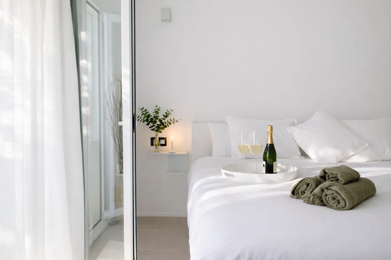 Casa Lux bedroom with champagne, towels and soft natural light
